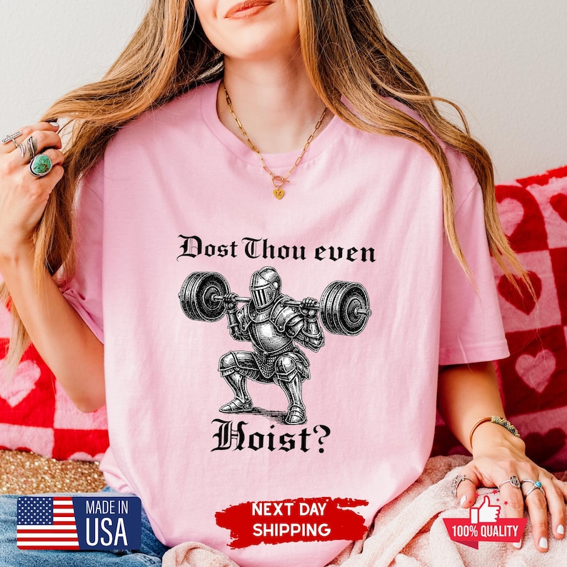 May include: Pink t-shirt with the text "Dost Thou even Hoist?" above a graphic of a knight lifting weights. The shirt also has a small American flag and the words "Made in USA".