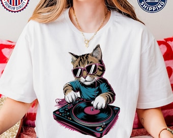 Op de afbeelding: Wit T-shirt met een afbeelding van een kat met een zonnebril en koptelefoon, die muziek mixt op een draaitafel.