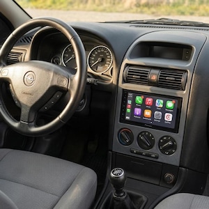 Puede incluir: Interior de coche con volante negro, indicadores y pantalla táctil Pioneer que muestra iconos de aplicaciones. El salpicadero es gris y negro, con rejillas de ventilación y mandos.