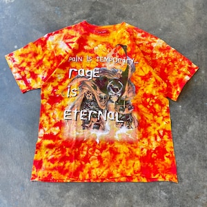 May include: A tie-dye t-shirt in shades of red, orange, and yellow. The shirt features a graphic of a character with the text "pain is temporary... rage is eternal."