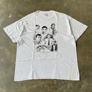 May include: A light gray t-shirt featuring a black and white graphic of several men. The graphic includes the text "The Men of Mayberry" at the bottom. The shirt is made of a soft material.