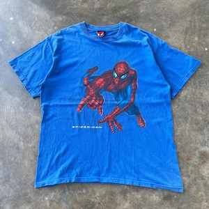 Pode incluir: Uma t-shirt azul brilhante de manga curta com um gr&aacute;fico da personagem Spider-Man numa posi&ccedil;&atilde;o agachada. A personagem &eacute; vermelha e azul com um padr&atilde;o de teia. O texto Spider-Man est&aacute; impresso a branco por baixo do gr&aacute;fico na frente.