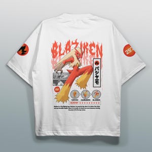May include: White t-shirt featuring a Blaziken graphic. The design includes the word "Blaziken" in red, a stylized image of the character, and Japanese text. The sleeves have orange circular designs with a black graphic and the number 257.