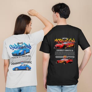 Puede incluir: Dos camisetas con diseños gráficos de coches deportivos. La camiseta blanca presenta un Porsche 911 Carrera 996 azul con el texto "911 Carrera 996". La camiseta negra presenta un Chevrolet Corvette C6 rojo con el texto "Chevrolet Corvette C6".