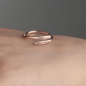 May include: A rose gold ring with the names "Jorge" and "Amanda" engraved on it.