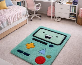 May include: A rectangular teal rug with a cartoon face design and a black border. The rug features a yellow plus sign, a blue triangle, a red circle, and other shapes. The rug is on a light-coloured carpet in a bedroom.