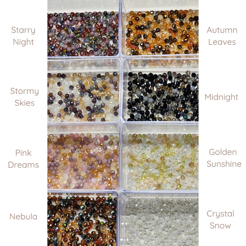 May include: Assortment of small glass beads in various colors, including black, white, gold, brown, pink, and clear. The beads are arranged in clear plastic containers labeled with names like "Starry Night", "Stormy Skies", "Pink Dreams", "Nebula", "Autumn Leaves", "Midnight", "Golden Sunshine", and "Crystal Snow".