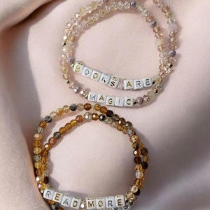Two sets of bracelets with phrases on them for book lovers: Books Are Magic and Read More Books