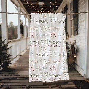 May include: A white blanket with the name "WESTON" and the initials "WN" in various colors. The blanket is hanging on a clothesline on a porch. The text is in shades of red, green, and blue.