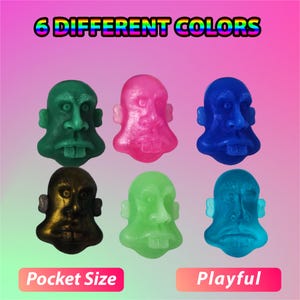 May include: Six colorful, pocket-sized, rubber figures of faces with different expressions.  The figures are green, pink, blue, gold, light green, and dark blue.  The text "6 DIFFERENT COLORS" is at the top of the image.  The text "Pocket Size" is at the bottom left of the image.  The text "Playful" is at the bottom right of the image.