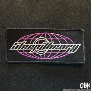 May include: A black, rectangular patch featuring the white text "Sleep Theory" within a pink globe design. This embroidered patch is designed for application on clothing or accessories.