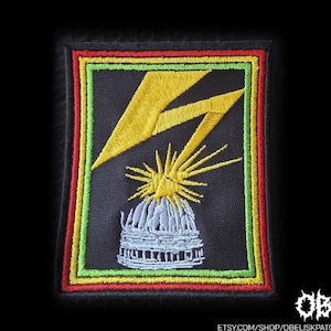 May include: A rectangular embroidered patch featuring a black background with a yellow lightning bolt striking a grey domed building. The design is framed by thin green and red borders. The text OBK and etsy.com/shop/obeliskpatches appears.