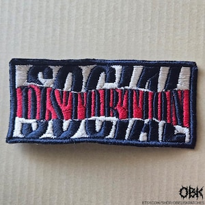 May include: Embroidered patch with the text "LOYALTY OVER ROYALTY" in white, red, and navy blue. The patch is rectangular and features a stitched design. The patch is likely for clothing or accessories.