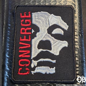 Puede incluir: Un letrero de madera hecho a mano con la palabra "Welcome" en una fuente juguetona. El letrero está pintado de blanco con un acabado envejecido y presenta un diseño floral decorativo en tonos rosas y verdes. Para uso en interiores o exteriores.