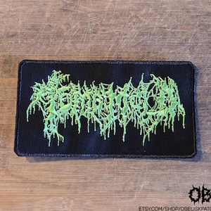 May include: A rectangular black fabric patch featuring bright lime green embroidery in a stylized, illegible, dripping font. The patch has a black stitched border and a textured surface, with the text etsy.com/shop/obeliskpatches in the corner.