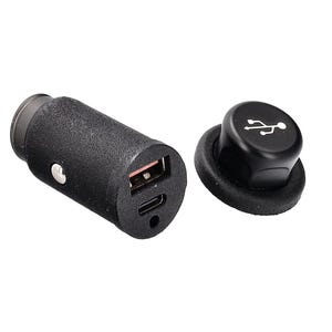 Può includere: Un caricatore per auto USB nero con superficie strutturata. Il caricatore ha una porta USB e una porta USB-C. Un tappo nero con un simbolo USB è accanto.