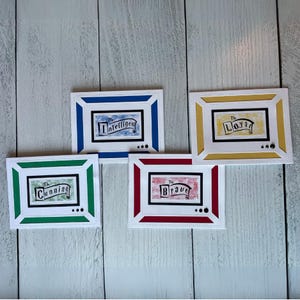 May include: Four handmade greeting cards with white borders and colorful frames in blue, yellow, green, and red. Each card features a banner with a word: "Intelligent", "Loyal", "Cunning", and "Brave".