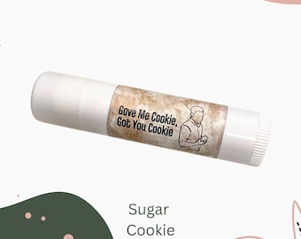 May include: White lip balm tube with a brown label featuring the text "Gave Me Cookie, Got You Cookie" and a line drawing of a person. The text "Sugar Cookie" is below the tube.