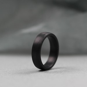 以下が含まれることがあります： 滑らかでマットな仕上がりの黒いカーボンファイバーリングです。