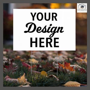 Könnte beinhalten: Ein weißes Schild mit dem schwarzen Text "YOUR Design HERE". Das Schild steht in Gras mit Herbstblättern in den Farben Rot, Orange und Gelb. Geeignet für den Außenbereich.