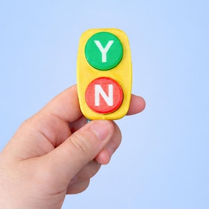 以下が含まれることがあります： 「Y」の文字が入った緑色の円と「N」の文字が入った赤色の円が付いた黄色の意思決定ツール。ツールは水色の背景に対して保持されています。「Y」と「N」は白で、ツールは長方形です。