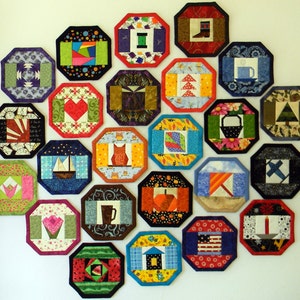 Könnte beinhalten: Eine Sammlung von 20 bunten achteckigen Stoffuntersetzern mit verschiedenen Designs, darunter ein Herz, ein Haus, ein Baum, eine Tasse, ein Stiefel, ein Kürbis, eine Kerze, ein Stern, ein Blatt, eine Eule, ein Fisch, eine Wassermelone und ein Weihnachtsbaum.