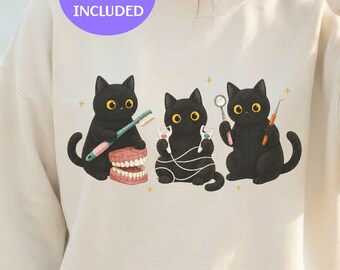 Könnte beinhalten: Ein cremefarbenes Sweatshirt mit einer Grafik von drei schwarzen Katzen mit großen gelben Augen. Eine Katze hält eine Zahnbürste und ein Zahnmodell, eine andere Zahnseide und die dritte einen Zahnspiegel und eine Sonde, mit kleinen Sternen.