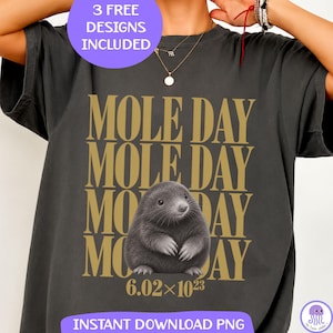 Op de afbeelding: Een antracietgrijs t-shirt met de gouden tekst MOLE DAY vier keer herhaald, een centrale illustratie van een mol en de wetenschappelijke notatie 6.02x10^23 eronder gedrukt. Het shirt bevat een paarse cirkelvormige afbeelding 3 FREE DESIGNS INCLUDED.