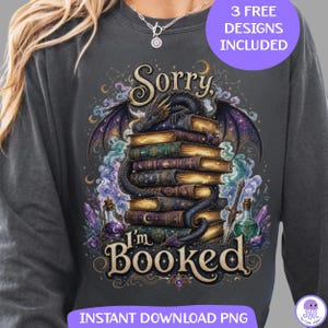 May include: A charcoal gray long-sleeve sweatshirt featuring a graphic print of a dragon coiled around a stack of antique books. The text reads Sorry, I'm BOOKED. The design includes purple and blue smoke, crystals, and potion bottles.