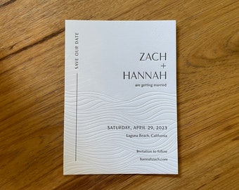 May include: Save the date card with a white background and black text. The card features a wave pattern and the text "Zach + Hannah are getting married. Saturday, April 29, 2023 Laguna Beach, California Invitation to follow hannahzach.com"