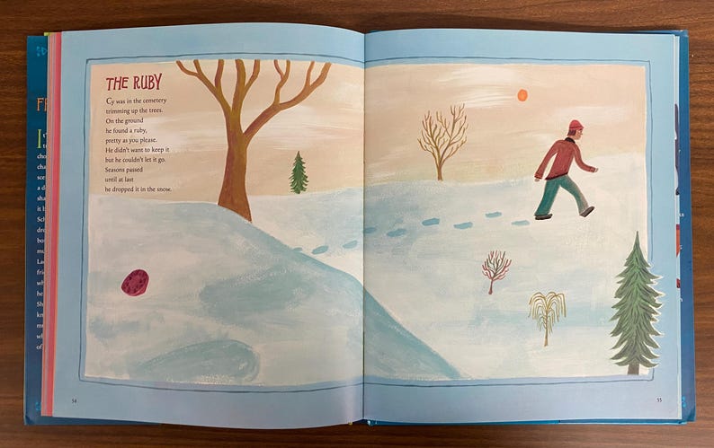 Puede incluir: Un libro abierto con una cubierta azul y una p&aacute;gina blanca que muestra un rub&iacute; rojo en un paisaje nevado. El texto en la p&aacute;gina dice "El Rub&iacute;" y un poema sobre una persona que encuentra un rub&iacute; en la nieve.