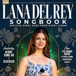 Può includere: La copertina di un Songbook di Lana Del Rey mostra la cantante che tiene un microfono, con un vestito floreale. La copertina include il testo "Lana Del Rey Songbook" e "Explore Every Song From Every Album."