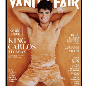 Op de afbeelding: Een Vanity Fair tijdschriftomslag met een persoon in een lichtoranje tanktop en bijpassende korte broek, liggend op een leemkleurige ondergrond. De tekst bevat 'VANITY FAIR', 'THE GLOBAL SPORTS ISSUE', 'KING CARLOS ALCARAZ' en diverse artikeltitels.