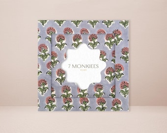 May include: A square, floral-patterned fabric with a light blue background and repeating pink and green flower designs. The fabric is layered with a white, star-shaped cutout in the center. The text "7 MONKIEES HOME" is visible.