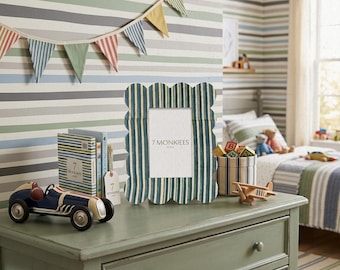 May include: A scalloped picture frame with a vertical blue and white striped pattern. The frame features the text 7 MONKIEES HOME printed in the center. The frame is constructed with a wavy edge design and a smooth finish, displaying a classic aesthetic.
