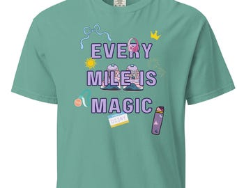 May include: A teal t-shirt with the text "Every Mile is Magic" in purple, yellow, and white. The shirt features cartoon graphics of running shoes, a bow, a crown, and other running-themed elements. The shirt is made of a soft material.