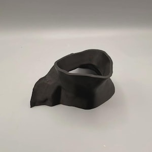 May include: A matte black, 3D-printed plastic component featuring a wide, irregular circular opening at the top that tapers down into a flared, asymmetrical base. The object has a smooth, solid surface with visible layer lines from the printing process.