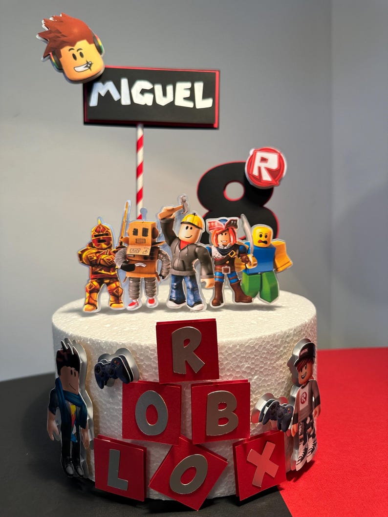 K&ouml;nnte beinhalten: Ein wei&szlig;er Kuchen, verziert mit Roblox-Figuren und einem Schild mit der Aufschrift "MIGUEL". Der Kuchen hat rote und silberne Akzente, darunter die Zahl "8" und das Wort "ROBLOX".