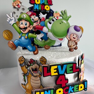 K&ouml;nnte beinhalten: Ein dekorierter Kuchen mit Super Mario-Charakteren. Der Kuchen ist mit bunten Ausschnitten von Mario, Luigi, Yoshi und Bowser verziert. Der Text "Super Niko" und "Level 4 Unlocked!" sind ebenfalls zu sehen.