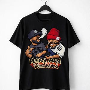 Puede incluir: Camiseta negra con una ilustración de dibujos animados de dos hombres con barba y sombreros. Uno está fumando y el otro sostiene un micrófono. El texto "Method Man Redman" se muestra en rojo y amarillo.