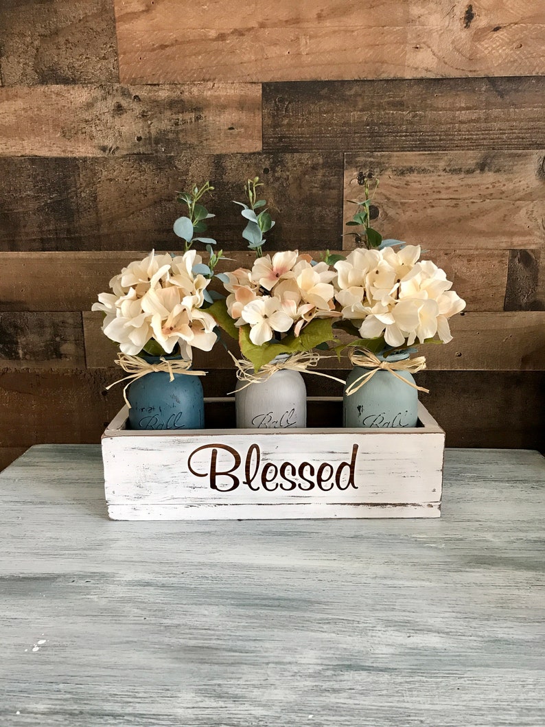 Centerpiece for dining room table. Three hand painted mason jars comes filled with one hydrangea and stem. You pick mason jar colors. Wood box has Blessed or change it and make it custom for you. Pick your own wording or put your last name.