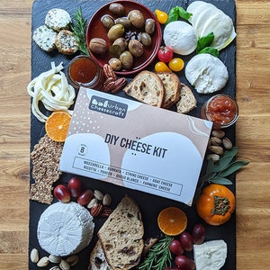 cheesemaking kit on slate cheese board with homemade cheeses and charcuterie pairings fruit bread olives