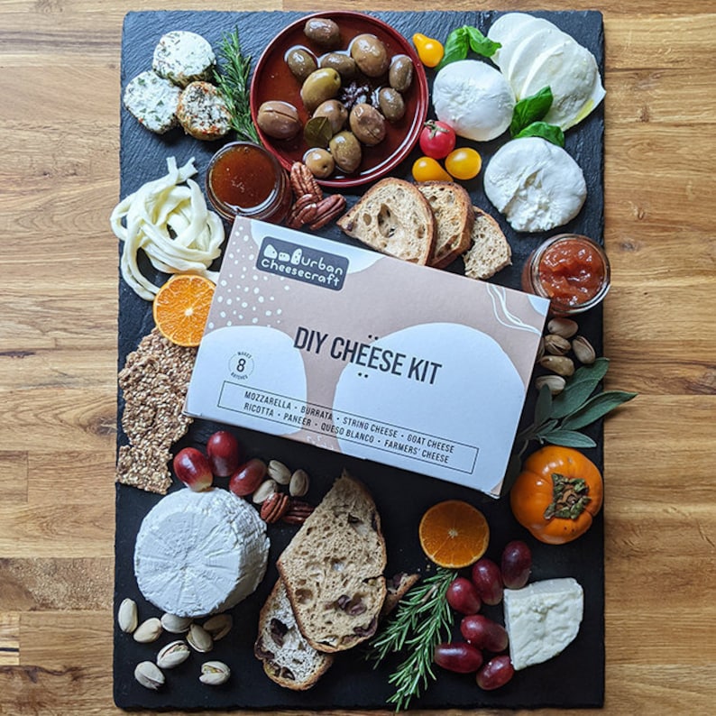 cheesemaking kit on slate cheese board with homemade cheeses and charcuterie pairings fruit bread olives