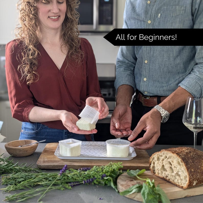 May include: A person holding a square cheese mold with a block of fresh cheese. Two other cheese molds with cheese are on a decorative tray. The image includes the text "All for Beginners!" and a loaf of bread.