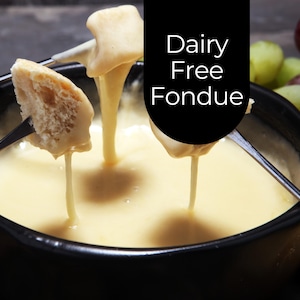 May include: A close-up of dairy-free fondue in a black bowl. Bread and other items are dipped into the creamy, yellow fondue. The image includes the text "Dairy Free Fondue" in white letters on a black background.