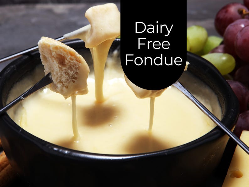 May include: A close-up of dairy-free fondue in a black bowl. Bread and other items are dipped into the creamy, yellow fondue. The image includes the text "Dairy Free Fondue" in white letters on a black background.