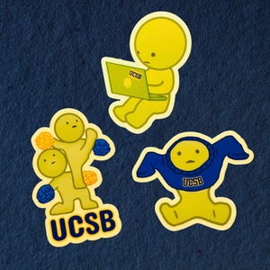 Puede incluir: Tres pegatinas amarillas de la UCSB sobre un fondo azul oscuro. Una pegatina muestra una figura amarilla usando una computadora portátil con "UCSB" en la pantalla. Otra muestra dos figuras, y la tercera muestra una figura con una sudadera azul de la UCSB.