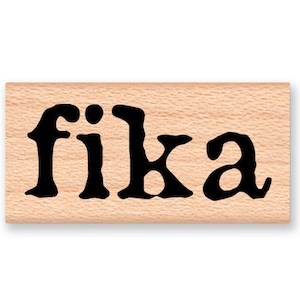 May include: A wooden stamp with the word "fika" printed in black ink.