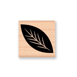 May include: A wooden stamp with a black silhouette of a leaf with veins.