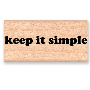 May include: Wooden stamp with the text "keep it simple" in black lettering.